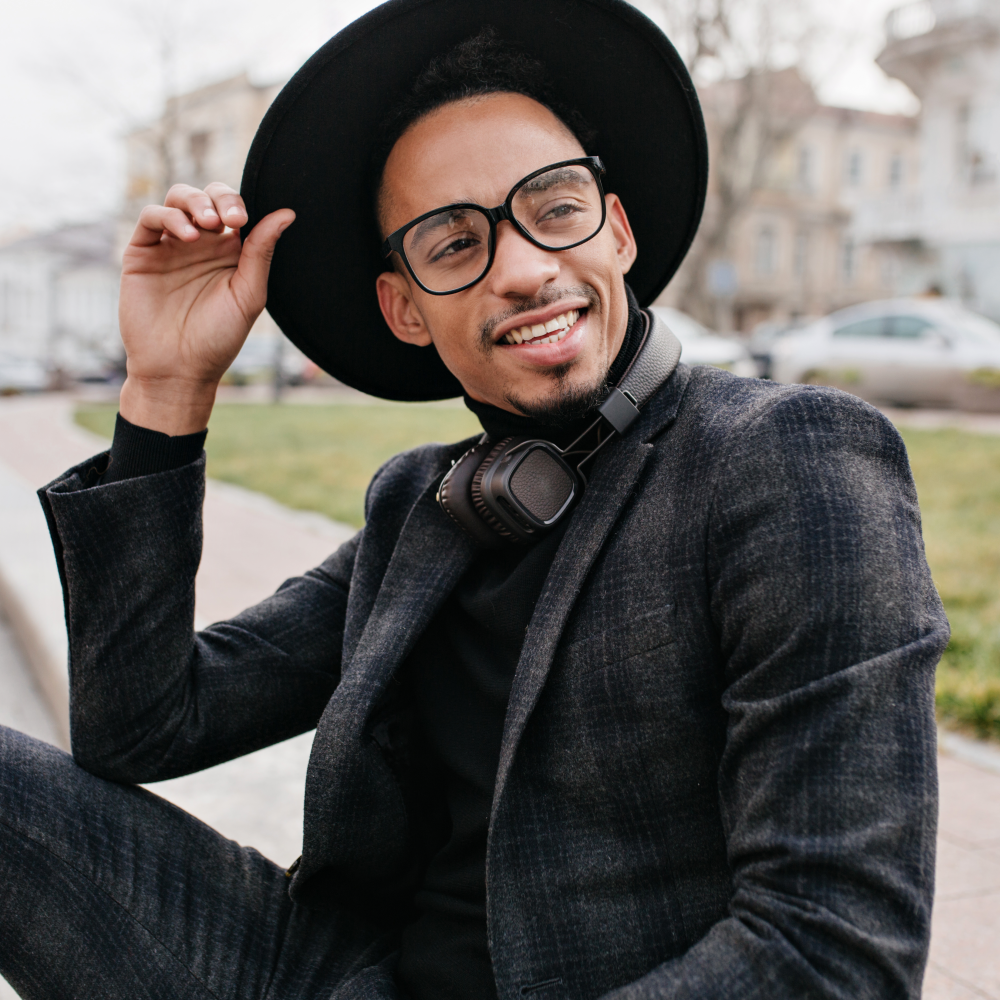 Man wearing stylish prescription glasses and a black hat, exuding urban sophistication.